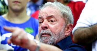 foto mostra ex-presidente lula apontando com o dedo para frente e uma cara assustada