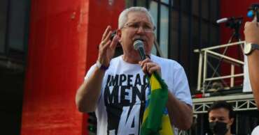 foto mostra antonio neto discursando em uma manifestação enquanto segura uma bandeira do brasil